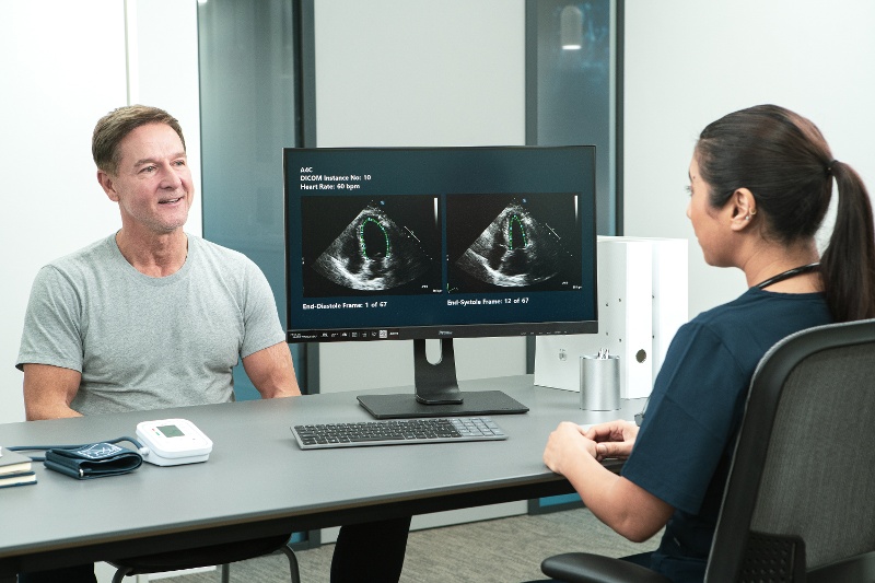 A patient and clinician sitting at a table discussing cardiac readings and treatment.