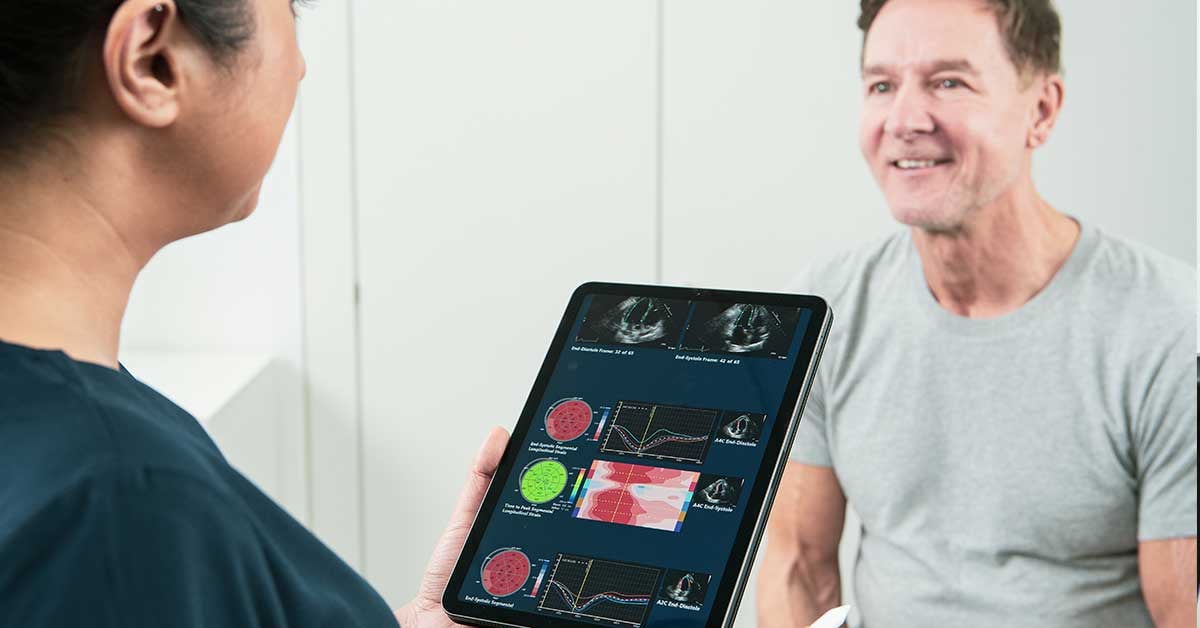 A clinician discussing the results of a heart echocardiogram with a patient. She is looking at results on a tablet screen provided by EchoGo software.